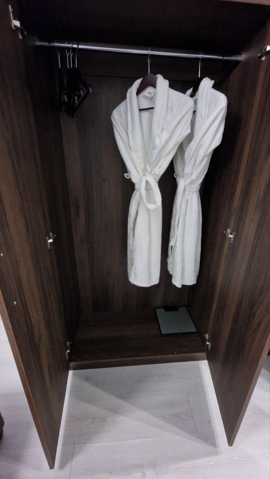 A walk-in closet with two white robes hanging on a rod.