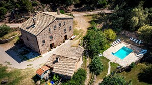 Un edificio de piedra con piscina y sillas de descanso.
