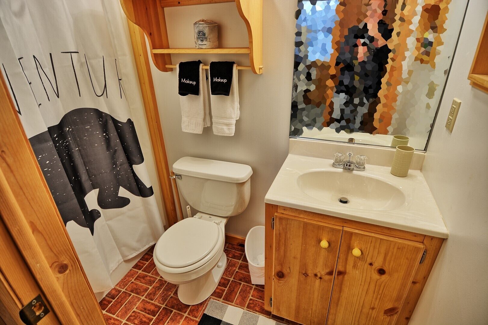 Ein Badezimmer mit Toilette, Waschbecken und einer Duschkabine mit einem schwarzen Elefantenmuster.