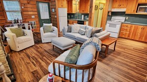 A cozy cabin interior with a living area featuring a sofa set, a wooden dining table, and a kitchen with wooden cabinets and appliances. - The Fairy Woods Cabin in Banner Elk, NC, offers a cozy retreat for up to 8 guests. (Banner Elk)