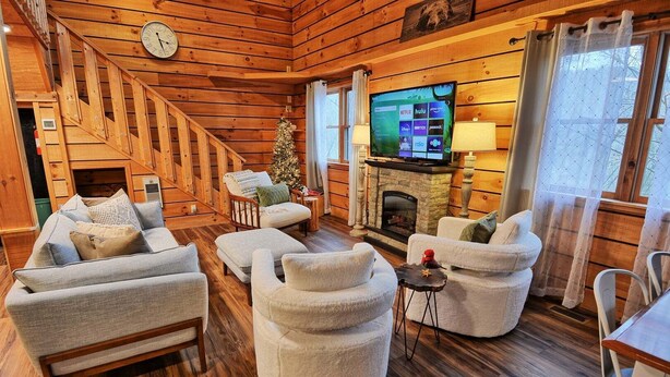 A cozy log cabin interior with a fireplace, a television, and a Christmas tree. - The Fairy Woods Cabin in Banner Elk, NC, offers a cozy retreat for up to 8 guests. (Banner Elk)