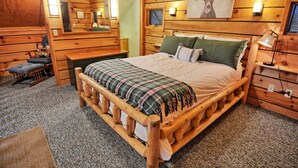 A wooden cabin-style bedroom with a bed, a dresser, a mirror, and a wall-mounted picture. - The Fairy Woods Cabin in Banner Elk, NC, offers a cozy retreat for up to 8 guests. (Banner Elk)