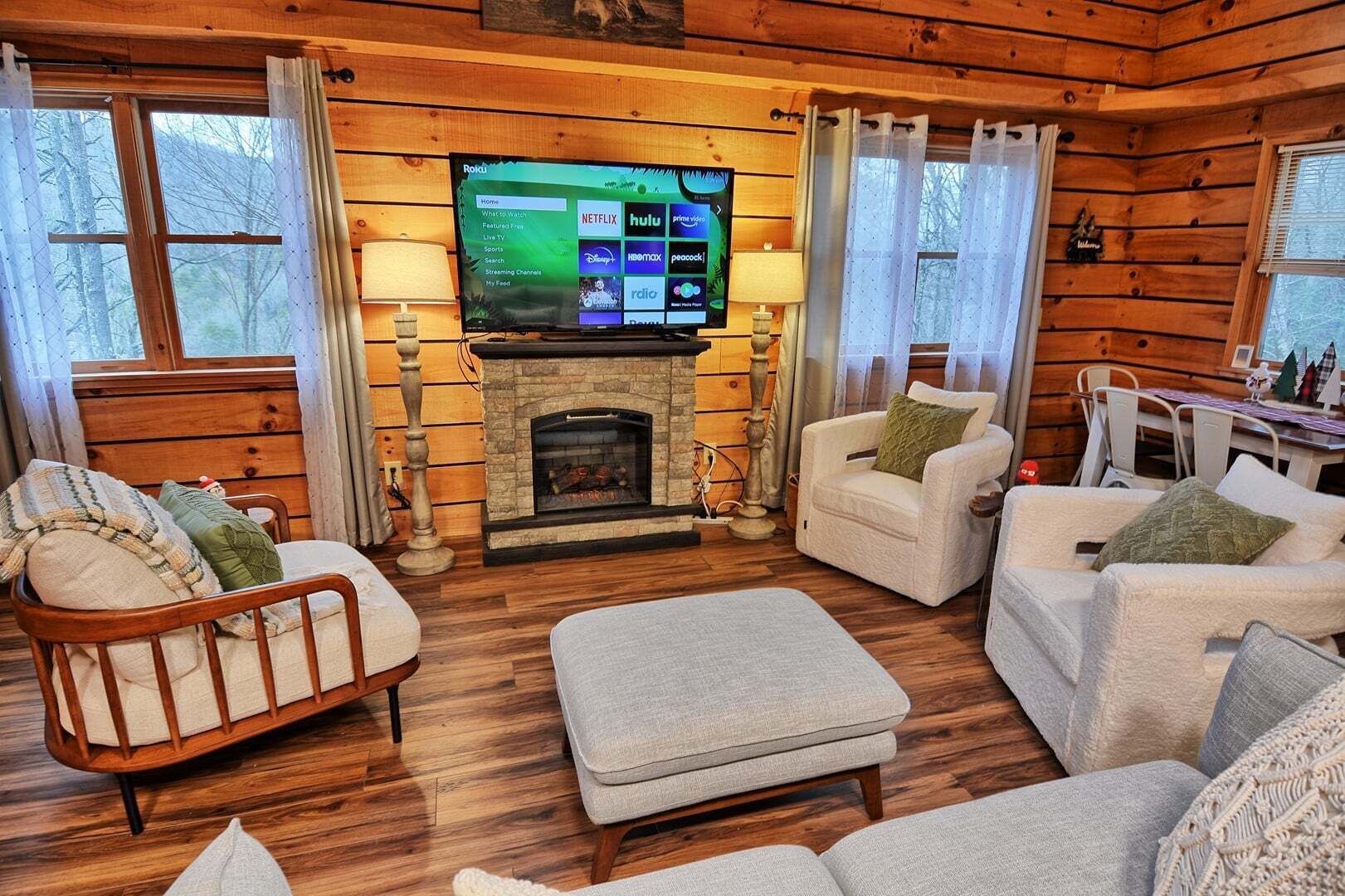 A cozy cabin interior with a stone fireplace, wooden walls, a television, and a comfortable seating area.