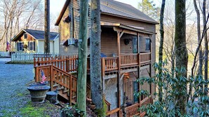A wooden cabin with a porch, a fenced yard, and a gravel driveway. - The Fairy Woods Cabin in Banner Elk, NC, offers a cozy retreat for up to 8 guests. (Banner Elk)