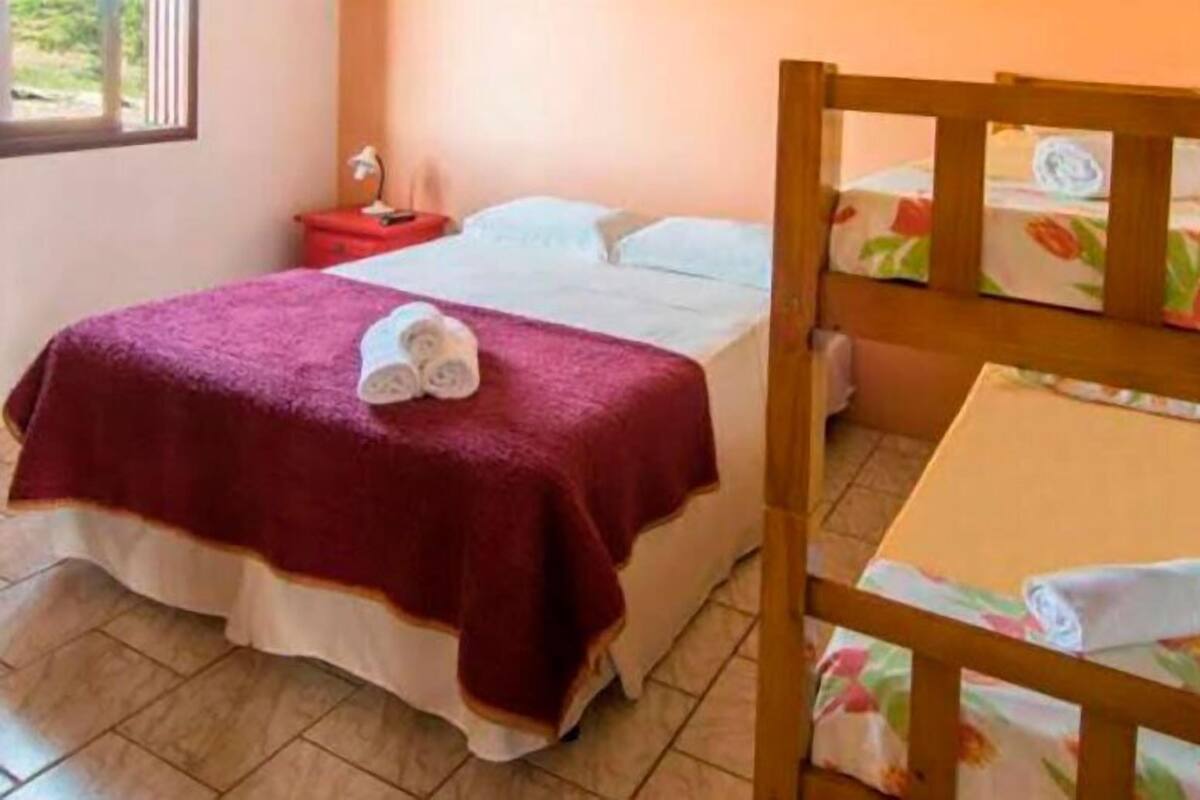 A single bed with a red blanket, a wooden headboard, and a small bedside table with a lamp.