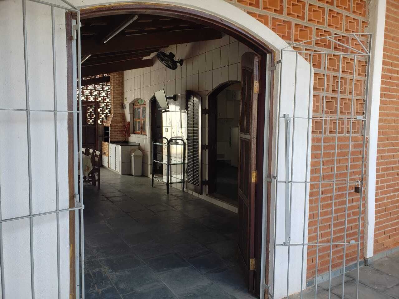 An interior corridor with a tiled floor, a brick wall, and a metal gate.