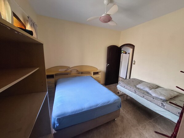 A bedroom with a bed, a dresser, a wardrobe, and a ceiling fan. - House with a Pool in Itanhaém – Family and Pets (Itanhaém)