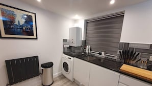 A modern kitchen with a washing machine, a radiator, and a sink.