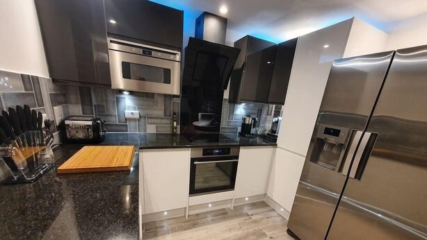 A modern kitchen with a stainless steel refrigerator, a built-in oven, and a microwave.