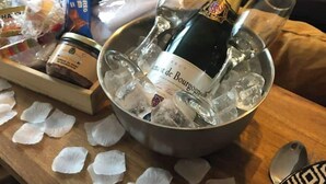 Een tafel met champagne, ijs, glazen en een doos popcorn.