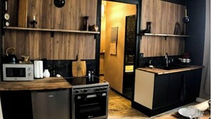 Een moderne keuken met houten planken, een inbouwoven en een compacte koelkast.