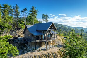 A log cabin with a balcony, surrounded by trees and a rocky landscape. - Cabin on the Rocks...Sit Back and take a Sip! (Sevierville)