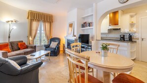 Una sala de estar moderna con sofá, sillón, televisor y mesa de comedor.