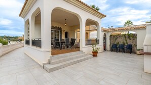 Un patio techado con una mesa y sillas, una planta en maceta y vistas del entorno.