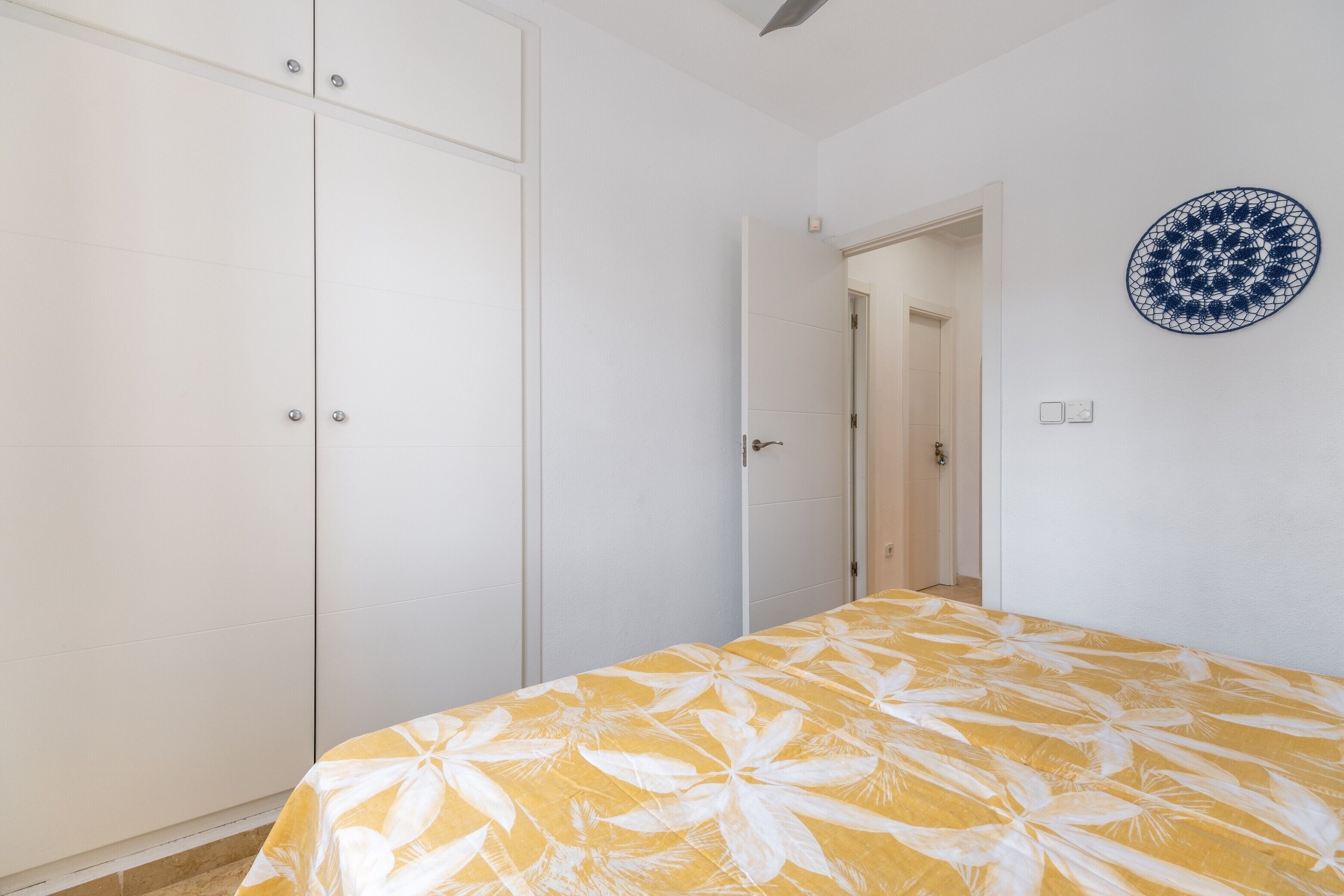 Une chambre à coucher avec un lit, une armoire, une porte et un élément de décoration murale.