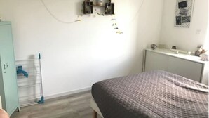 Un dormitorio con cama, radiador, armario y escritorio con espejo.