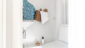 A bathroom with a white sink, a blue patterned wall, and a white towel hanging on a shelf. - Cozy and peaceful studio apartment (Helsinki)