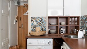 A compact kitchen with a washing machine, a sink, and a tiled backsplash. - Cozy and peaceful studio apartment (Helsinki)