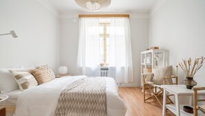 A bedroom with a large bed, bedside tables, a desk, and a chair. - Cozy and peaceful studio apartment (Helsinki)
