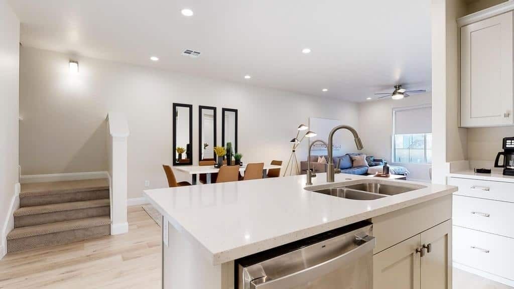 A modern kitchen with a central island, built-in appliances, and a dining area with a sofa and chairs.
