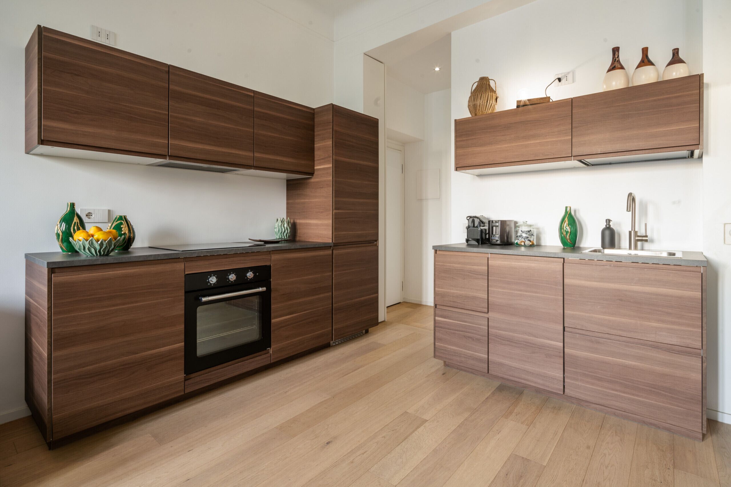 A modern kitchen with wooden cabinetry, a built-in oven, and a countertop with decorative items.