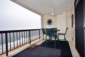 A balcony with a view of the ocean, a ceiling fan, and a table with chairs. - Comfortable, spacious 2 bedroom oceanfront condo with free WiFi, and a covered balcony with a wonderful ocean view located uptown just steps to the beach! (Ocean City)