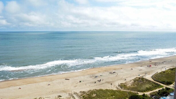 A beach with a sandy shore, waves, and a clear sky. - Comfortable, spacious 2 bedroom oceanfront condo with free WiFi, and a covered balcony with a wonderful ocean view located uptown just steps to the beach! (Ocean City)