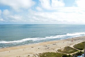 Ein Strand mit sandigem Ufer, Wellen und blauem Himmel.