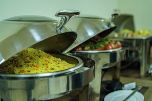 A buffet setup with multiple stainless steel chafing dishes containing various dishes.