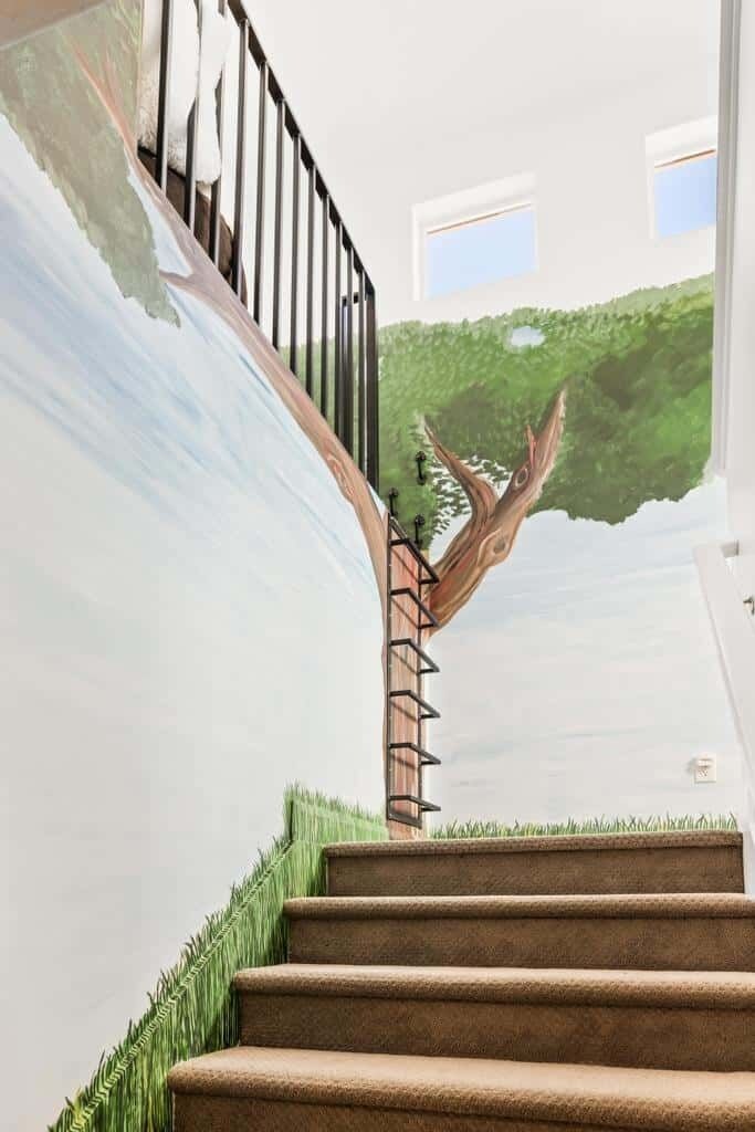 Una escalera con barandilla, un mural en la pared y una ventana.
