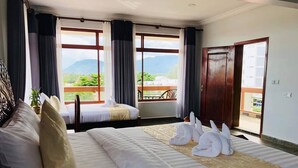 Habitación de hotel con dos camas, un balcón y vistas a la montaña, además de una puerta que da a un espacio exterior.