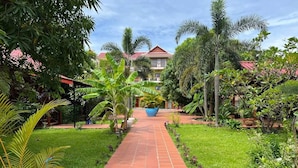 Un sendero conduce a un edificio rodeado de exuberante follaje y palmeras.