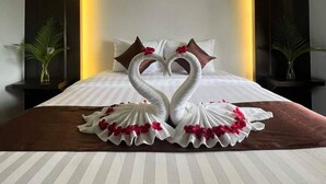 Una habitación de hotel con una cama que tiene una decoración con forma de cisne y un cuadro colgado encima.