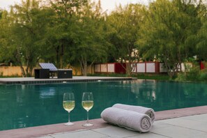 A swimming pool with two glasses of white wine and a rolled towel on the edge. - Shahpura Abhaneri Resort (Baswa)
