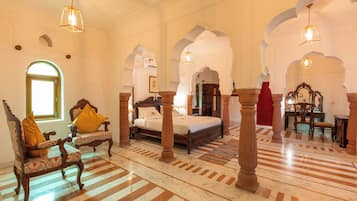 A spacious room with a large bed, ornate wooden furniture, and a patterned floor.
