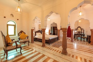 A spacious room with a large bed, ornate wooden furniture, and a patterned floor. - Shahpura Abhaneri Resort (Baswa)