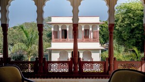 A traditional building with a balcony, ornate railings, and a view of lush greenery. - Shahpura Abhaneri Resort (Baswa)