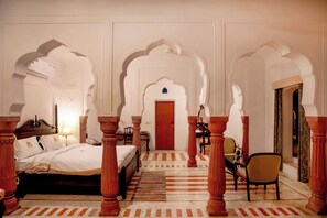 A traditional room with a bed, a desk, and a chair, featuring ornate arches and a patterned floor. - Shahpura Abhaneri Resort (Baswa)