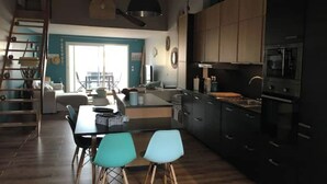 Una cocina moderna con armarios oscuros, una isla central y un comedor con dos sillas.