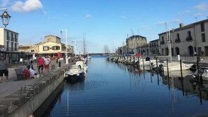 Un puerto deportivo con barcos amarrados a lo largo de una vía fluvial tranquila, rodeado de edificios y un cielo despejado.