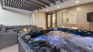 Moderni spa-alue, jossa on poreallas, sohva ja tunnelmallinen takka.