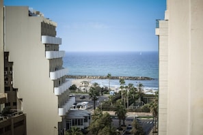 A high-rise building with balconies overlooking a beach and ocean.
