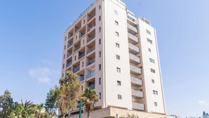 Um edifício residencial com várias andares, varandas, telhado plano e céu claro.