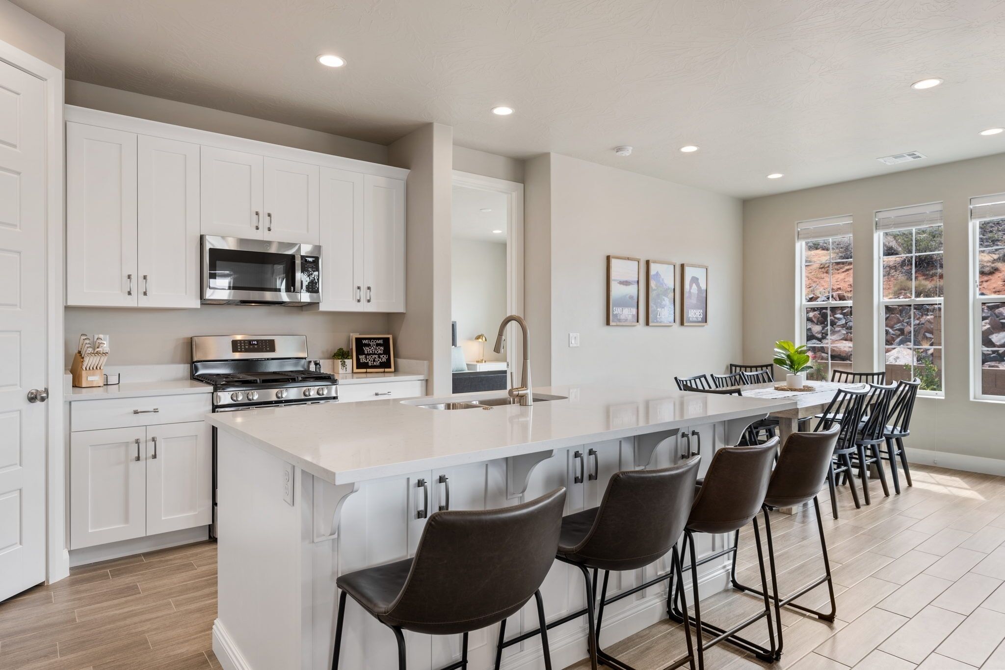 A modern kitchen with white cabinets, a stainless steel microwave, a stove, and a large island with bar stools.