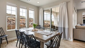 A dining area with a wooden table, black chairs, and a view of a desert landscape through large windows.