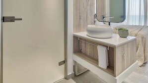 Een moderne badkamer met een grote spiegel, een witte wasbak en een houten opbergmeubel.