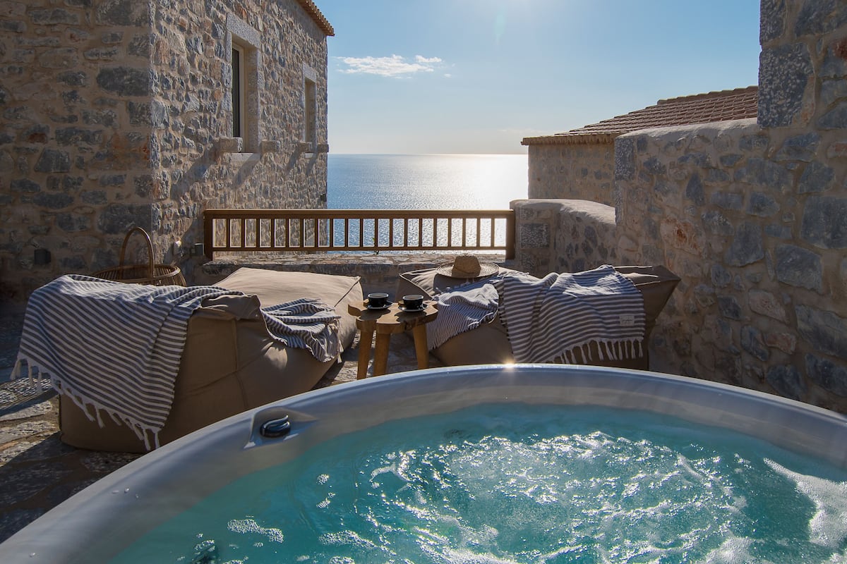 A stone building with a hot tub and outdoor seating.