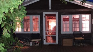 Eine Holzhütte mit Veranda, zwei Stühlen und einer Bank.