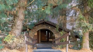 A rustic stone archway leading to a wooden door, surrounded by pine trees. - Husky Cosy 2 Bed Alpine Apartment Views & Balcony (Saint-Gervais-les-Bains)