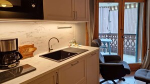 A compact kitchen with a sink, a coffee maker, and a microwave. There is a small dining area with two chairs and a table. - Husky Cosy 2 Bed Alpine Apartment Views & Balcony (Saint-Gervais-les-Bains)